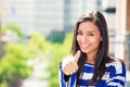 Woman with thumbs up on city background