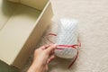 Woman tie a red ribbon on gift wrapped with bubble sheet before putting into carton for parcel Royalty Free Stock Photo