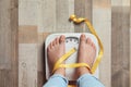 Woman with tied legs measuring her weight using scales Royalty Free Stock Photo