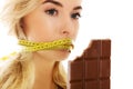 Woman with tied mouth holding bar of chocolate