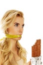 Woman with tied mouth holding bar of chocolate