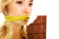 Woman with tied mouth holding bar of chocolate