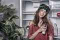 Woman with tired look standing next to open fridge. Girl holding glass of milk. Lady with curly hair and green headband Royalty Free Stock Photo