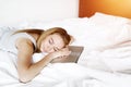 Woman tired of work sleep at laptop bed with white linen at home Royalty Free Stock Photo