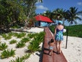 Woman and toddler are walking on a pathway towards wooden house with red roof