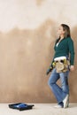 Woman With Toolbelt And Drill Leaning Against Wall Royalty Free Stock Photo