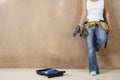 Woman With Toolbelt And Drill Leaning Against Wall