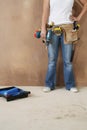 Woman With Toolbelt And Drill Leaning Against Wall Royalty Free Stock Photo