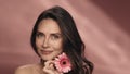 A woman touches a gerbera flower to her perfect skin of face. Portrait of a woman with a gerbera flower in the studio on Royalty Free Stock Photo