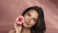 A woman touches a gerbera flower to her perfect skin of face. Portrait of a woman with a gerbera flower in the studio on Royalty Free Stock Photo