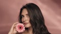 A woman touches a gerbera flower to her perfect skin of face. Portrait of a woman with a gerbera flower in the studio on Royalty Free Stock Photo