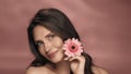 A woman touches a gerbera flower to her perfect skin of face. Portrait of a woman with a gerbera flower in the studio on Royalty Free Stock Photo