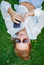 Woman touching cell phone and lying on meadow Royalty Free Stock Photo