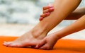 Woman touching her clean foot, one hand in a heel and other in her leg, background of orange color Royalty Free Stock Photo