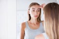 Woman touching her forehead while looking in the mirror in light room, beauty concept,wrinkles Royalty Free Stock Photo