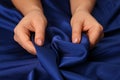 Woman touching silky blue fabric, closeup view