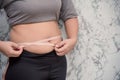 Woman touching stomach holding measuring tape ,Obese  with fat belly in dieting concept. touching stomach holding measuring tape Royalty Free Stock Photo