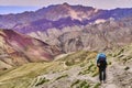 Woman tourist with a backpack climbing steep slope with beautiful colorful Himalaya mountains in the background, Ladakh, India Royalty Free Stock Photo