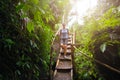 Woman tourist with backpack goes down bamboo stairs in jungle in