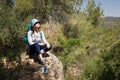 Woman tourist backpacker sitting resting stone hiking forest landscape