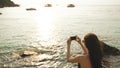 Woman tourist on beach island taking photograph of sunset with smartphone on holiday of boat and skyline view Royalty Free Stock Photo