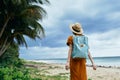 Woman tourist with blue backpack look at tall palm trees on the island landscape