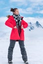 Woman tourist dressed in red winter jacket, sports pants, trekking boots stands in winter mountains Royalty Free Stock Photo