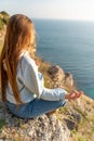 Woman tourist enjoying the sunset over the sea mountain landscape. Sits outdoors on a rock above the sea. She is wearing Royalty Free Stock Photo