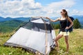 Woman tourist hiking in mountain trail, enjoying summer sunny morning in mountains near tent Royalty Free Stock Photo