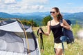 Woman tourist hiking in mountain trail, enjoying summer sunny morning in mountains near tent Royalty Free Stock Photo