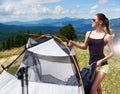 Woman tourist hiking in mountain trail, enjoying summer sunny morning in mountains near tent Royalty Free Stock Photo