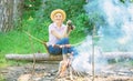 Woman tourist holds binoculars while sits on log near bonfire. Observing nature concept. Girl enjoy hike in forest Royalty Free Stock Photo