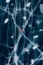 Woman tourist on ice skates and with long red scarf on frozen cracks lake Baikal, aerial top view