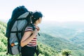 A woman tourist with a large camping backpack on an expedition stands on top and looks at the landscape.