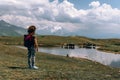 A woman tourist, next to a high mountain lake in which cows graze. Sunny day, trips. Koruldi Lakes, Mestia, Georgia. Copy space Royalty Free Stock Photo