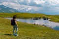 A woman tourist, next to a high mountain lake in which cows graze. Sunny day, trips. Koruldi Lakes, Mestia, Georgia. Copy space Royalty Free Stock Photo