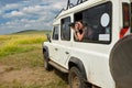 Woman tourist on safari in Africa, travel in Kenya, watching wildlife in savanna with binoculars