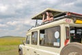 Woman tourist on safari in Africa, travel in Kenya, watching wildlife in savanna with binoculars