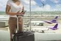 Woman tourist standing with luggage at airport window while waiting at boarding gate before departure at lounge. Travel lifestyle Royalty Free Stock Photo