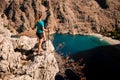 Woman tourist stands on stone and enjoying view of mountain landscape and sea bay. Royalty Free Stock Photo