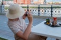 Woman tourist in a straw hat taking photo of her coffe and desert on plastic tray in street cafe Royalty Free Stock Photo