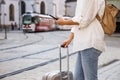 Woman tourist with suitcase and smart phone waiting for tram on street Royalty Free Stock Photo