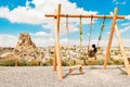 Woman tourist swinging in Cappadocia on vacation. Uchisar Castle, town in Cappadocia, Turkey near Goreme. Cappadocia landscape and Royalty Free Stock Photo