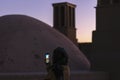 Woman tourist takes pictures of the windtower wind catcher - traditional Iranian architectural element to create natural ventila