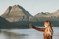 Woman tourist taking selfie by smartphone Travel Lifestyle concept adventure vacations outdoor Norway sunset mountains and sea Royalty Free Stock Photo