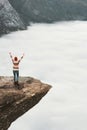 Woman tourist on Trolltunga rocky cliff raised hands