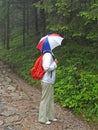 A woman tourist with an umbrella on her head will look into the woods on a rocky path. Tatra mountains, Poland Royalty Free Stock Photo