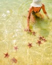 Woman tourist visit star fish beach pick starfish in famous tropical Koh Rong island, Cambodia. Touristy sightseeing famous