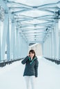 Woman tourist Visiting in Biei, Traveler in Sweater sightseeing Shirahige Waterfall bridge with Snow in winter. landmark and