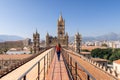 Woman tourist visitor walking on the rooftop catwalk of the Palermo Cathedral or Cattedrale di Palermo with bell towers in the